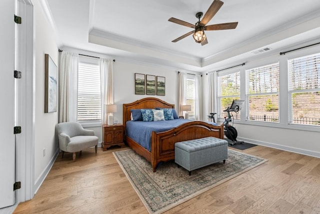 bedroom featuring light wood finished floors, a raised ceiling, baseboards, and ornamental molding