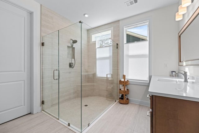 full bathroom featuring vanity, baseboards, visible vents, and a stall shower