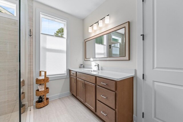 bathroom with vanity, baseboards, and a tile shower