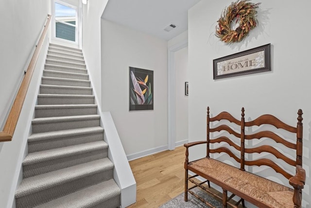 staircase with visible vents, baseboards, and wood finished floors