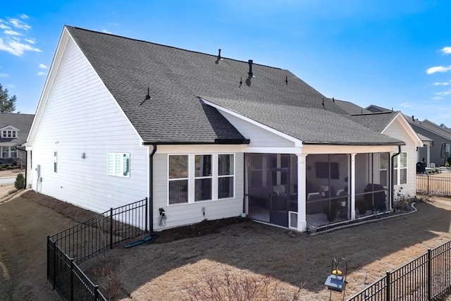 rear view of property with fence, roof with shingles, and a sunroom