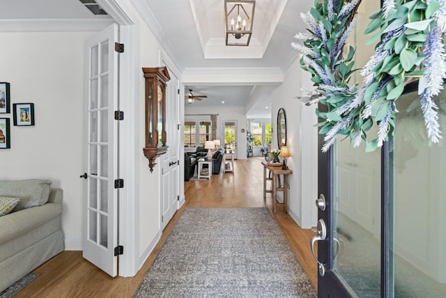 entryway featuring french doors, a raised ceiling, crown molding, and wood finished floors