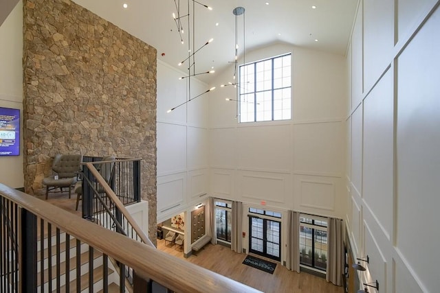 stairway featuring a decorative wall, high vaulted ceiling, and wood finished floors