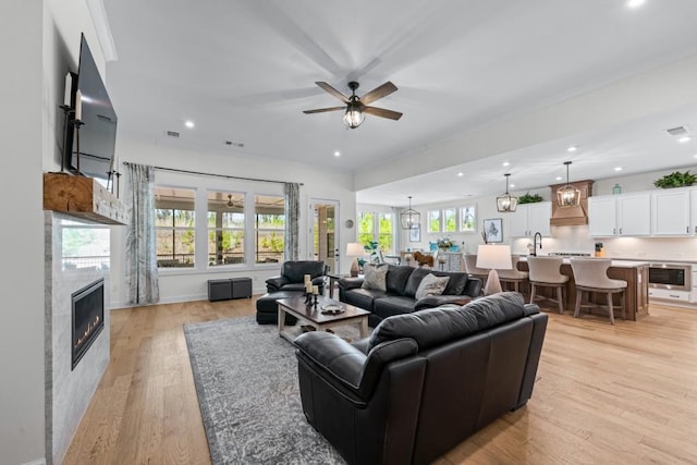 living area with plenty of natural light, a fireplace, crown molding, and light wood-style floors