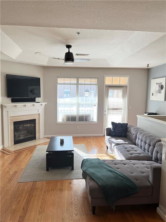 living room with ceiling fan, a textured ceiling, and light hardwood / wood-style flooring