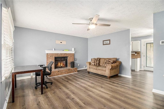 home office with a textured ceiling, a fireplace, dark hardwood / wood-style floors, and ceiling fan