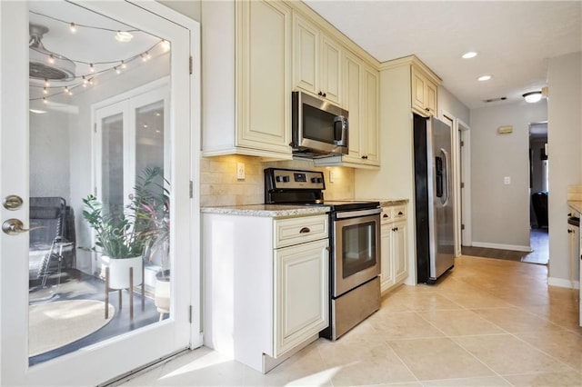 kitchen featuring light tile patterned flooring, tasteful backsplash, cream cabinets, and appliances with stainless steel finishes