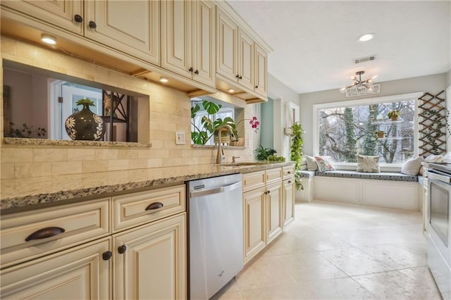 kitchen with stainless steel dishwasher, light stone countertops, and cream cabinets