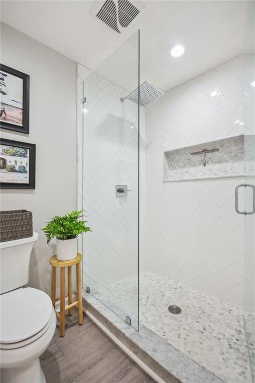 bathroom with hardwood / wood-style floors, walk in shower, and toilet