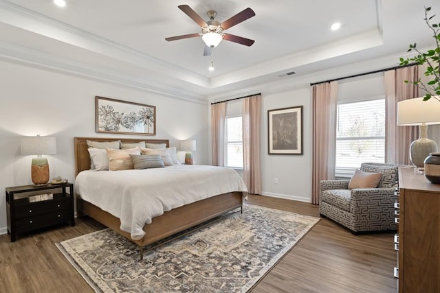 bedroom featuring a raised ceiling, ceiling fan, dark wood-type flooring, and ornamental molding