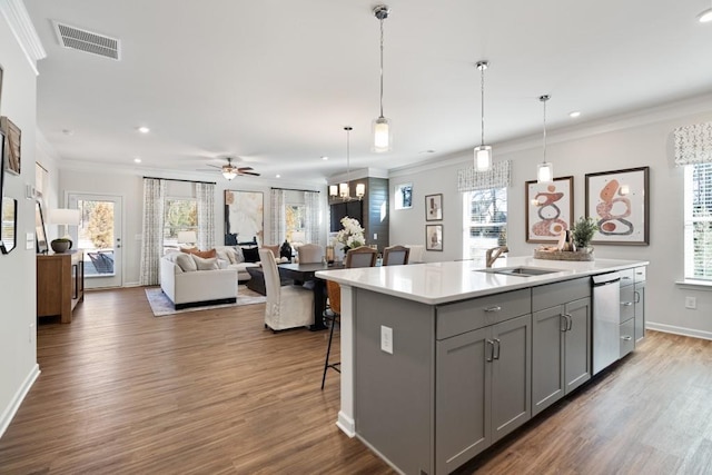 kitchen featuring sink, hanging light fixtures, stainless steel dishwasher, gray cabinets, and a center island with sink