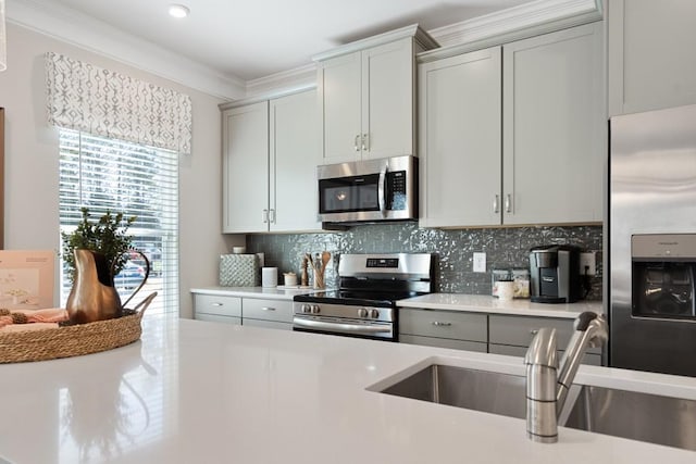 kitchen featuring sink, crown molding, gray cabinets, appliances with stainless steel finishes, and tasteful backsplash