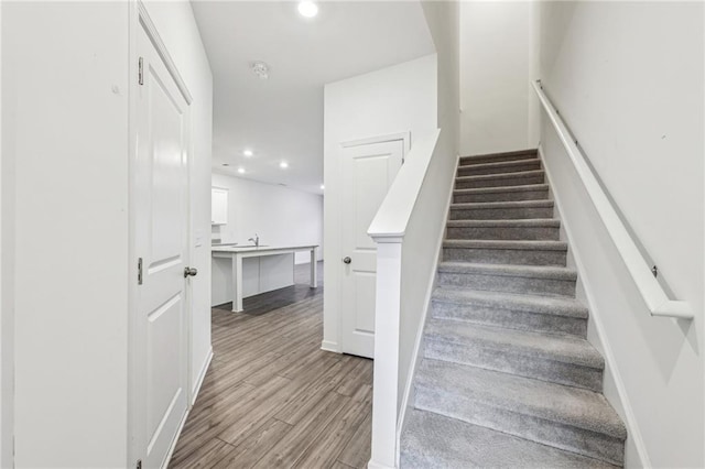 staircase with hardwood / wood-style flooring and sink