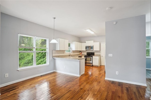 kitchen with backsplash, pendant lighting, kitchen peninsula, stainless steel appliances, and white cabinets