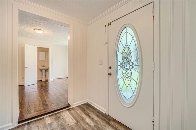 foyer entrance featuring crown molding, sink, wood-type flooring, and a textured ceiling