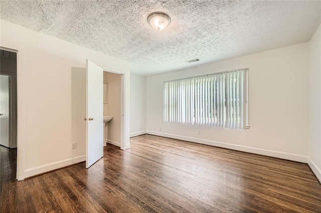 interior space with a textured ceiling and dark hardwood / wood-style flooring