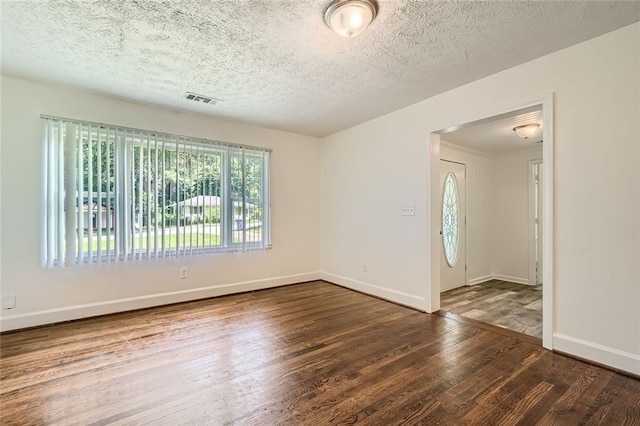 spare room featuring a textured ceiling and dark hardwood / wood-style flooring