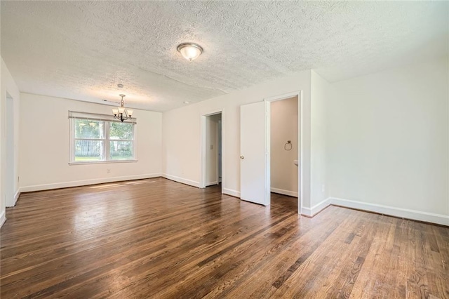 empty room featuring a notable chandelier, dark hardwood / wood-style floors, and a textured ceiling