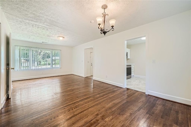 spare room with dark hardwood / wood-style flooring, a textured ceiling, and an inviting chandelier