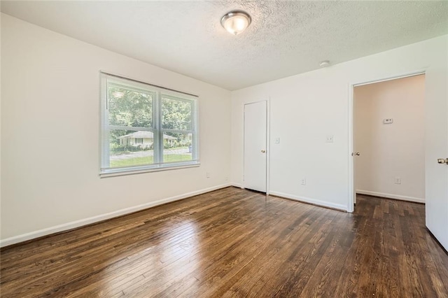 spare room featuring a textured ceiling and dark wood-type flooring