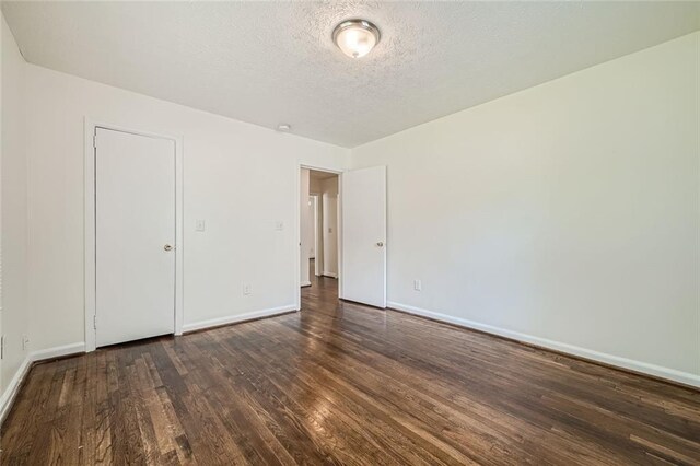 unfurnished bedroom with dark hardwood / wood-style flooring and a textured ceiling