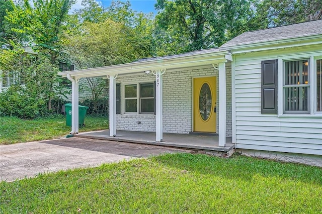 view of exterior entry with a lawn and a porch