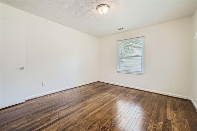 empty room featuring a textured ceiling and dark hardwood / wood-style floors