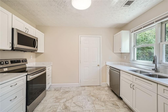 kitchen with a textured ceiling, sink, white cabinetry, and stainless steel appliances