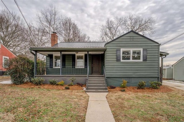 4131 Carroll St, Covington, GA 30014 - bungalow-style home with a chimney, covered porch, a front lawn, and a metal roof