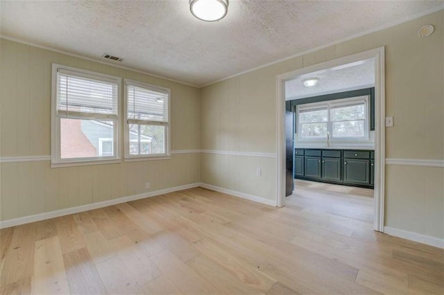4131 Carroll St, Covington, GA 30014 - empty room featuring light wood finished floors, a textured ceiling, crown molding, and a decorative wall