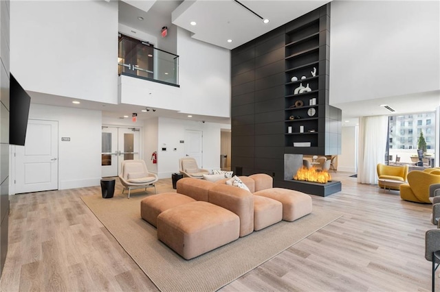 3324 Peachtree Rd NE Unit 1813, Atlanta, GA 30305 - living area featuring a towering ceiling, a multi sided fireplace, light wood-style floors, baseboards, and french doors