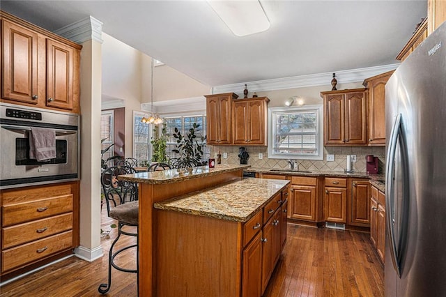 kitchen with light stone countertops, a kitchen breakfast bar, dark hardwood / wood-style flooring, a notable chandelier, and appliances with stainless steel finishes