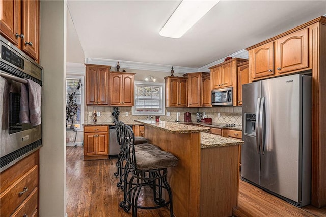 kitchen featuring ornamental molding, tasteful backsplash, a kitchen island, a kitchen bar, and stainless steel appliances