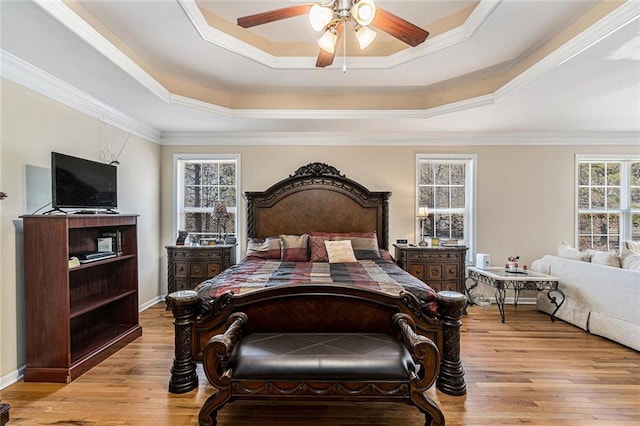 bedroom with a tray ceiling, ceiling fan, crown molding, and light hardwood / wood-style floors