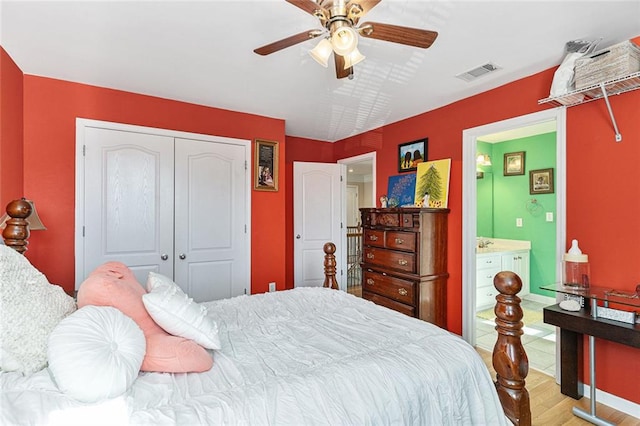 bedroom featuring hardwood / wood-style flooring, ceiling fan, ensuite bath, and a closet