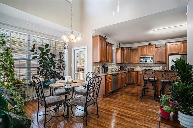 dining space featuring crown molding, dark wood-type flooring, sink, and an inviting chandelier