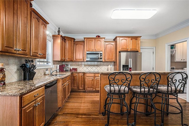 kitchen with sink, a center island, light stone counters, crown molding, and appliances with stainless steel finishes