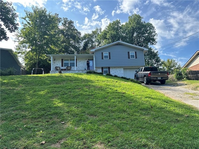 split level home featuring driveway, an attached garage, fence, and a front yard