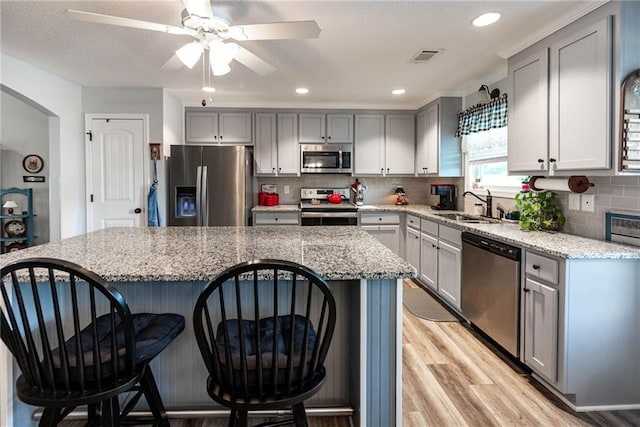 kitchen featuring ceiling fan, a breakfast bar area, stainless steel appliances, and gray cabinetry