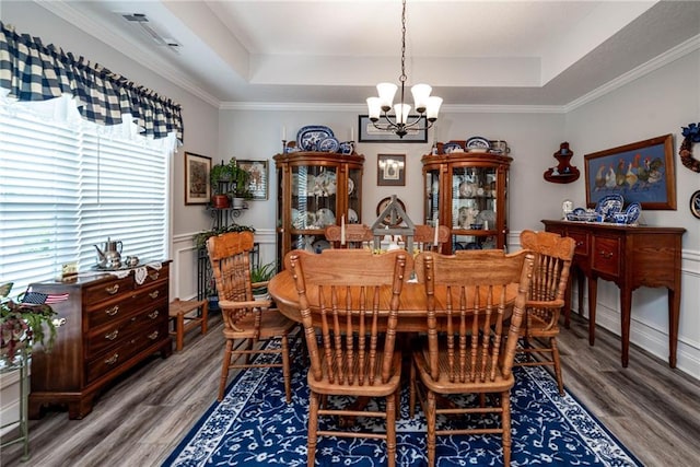 dining room featuring wood finished floors, ornamental molding, a chandelier, and a tray ceiling