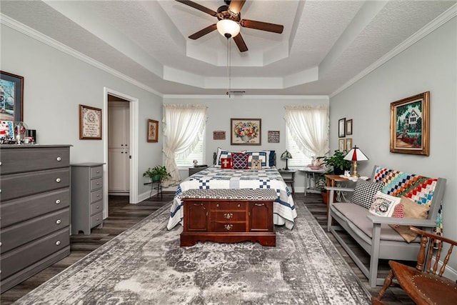 bedroom with dark wood finished floors, baseboards, crown molding, and a raised ceiling