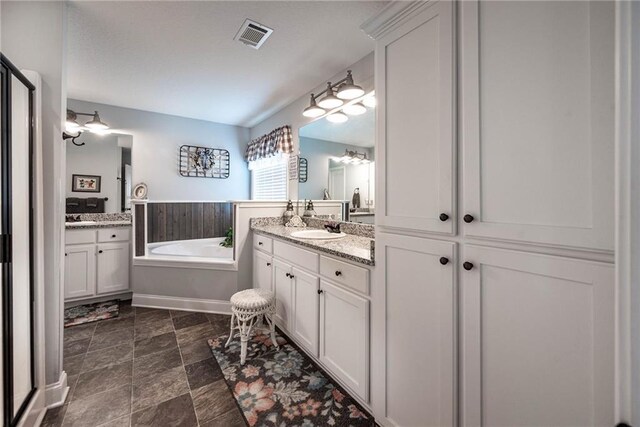 bathroom with a bath, two vanities, visible vents, and a sink