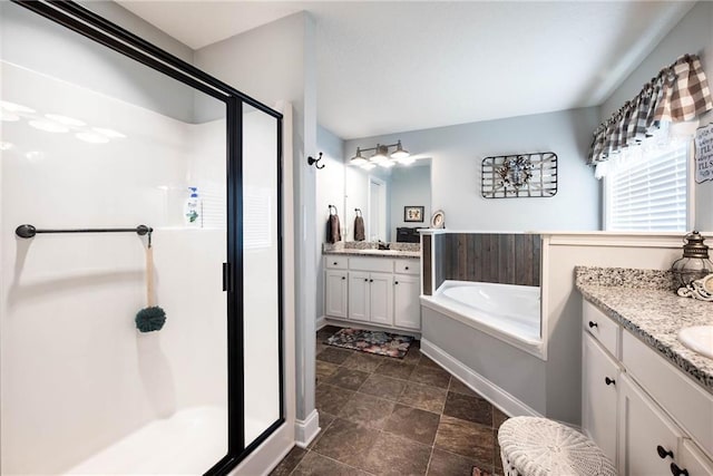 bathroom featuring a bath, two vanities, a sink, a stall shower, and baseboards