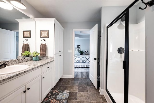 ensuite bathroom featuring connected bathroom, baseboards, vanity, and a stall shower