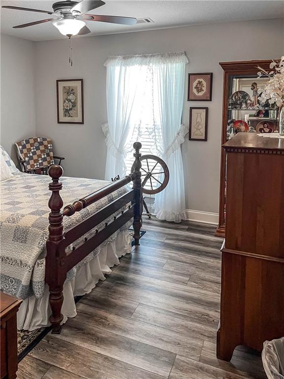 bedroom with ceiling fan, baseboards, and wood finished floors