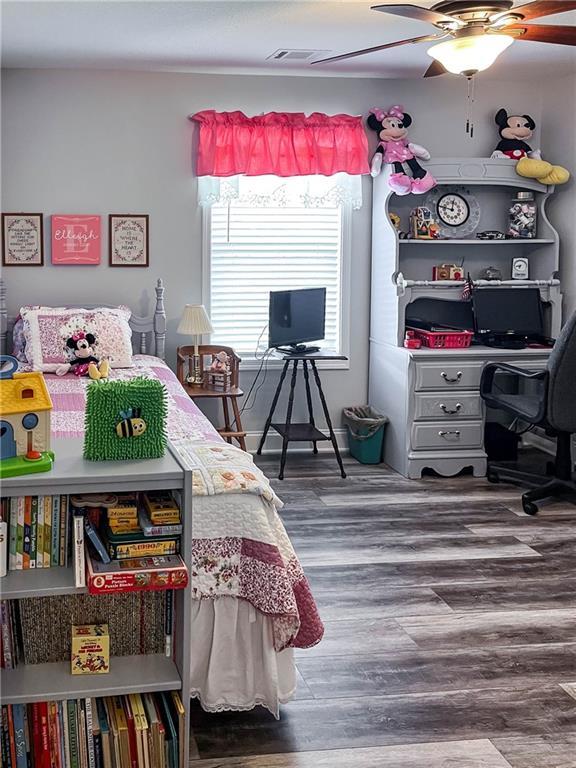 bedroom featuring a ceiling fan, wood finished floors, and visible vents