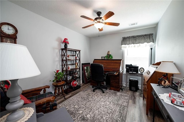 office featuring ceiling fan, wood finished floors, and visible vents