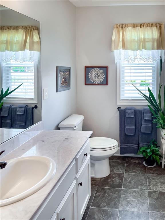 bathroom featuring stone finish floor, toilet, and vanity