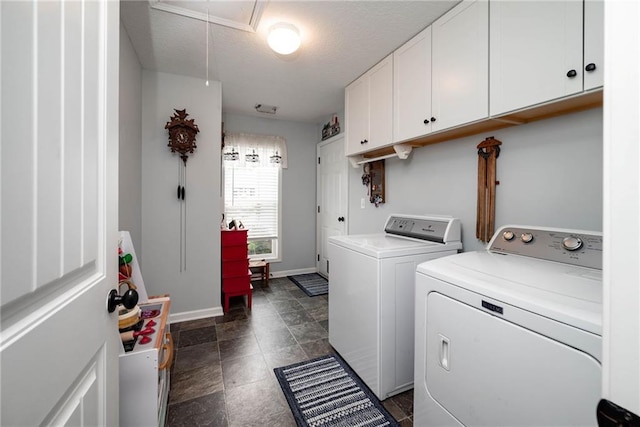clothes washing area featuring baseboards, separate washer and dryer, cabinet space, a textured ceiling, and attic access