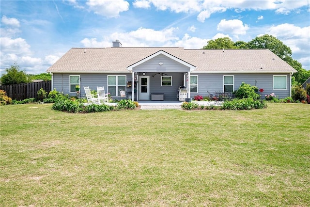 back of house with a chimney, fence, a patio, and a lawn